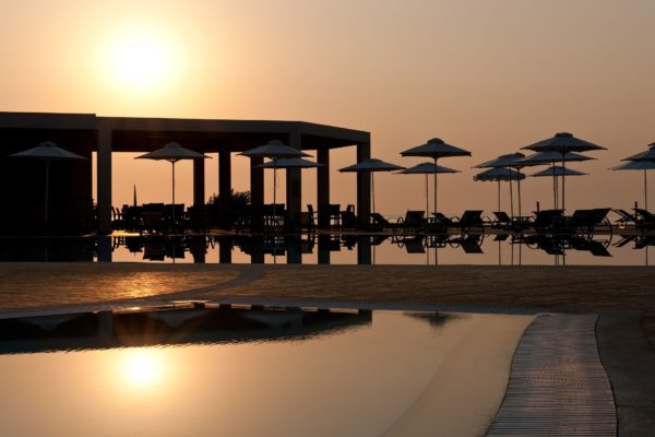 Sun setting over the sea at Apollo Blue Hotel, reflecting on the pool's surface