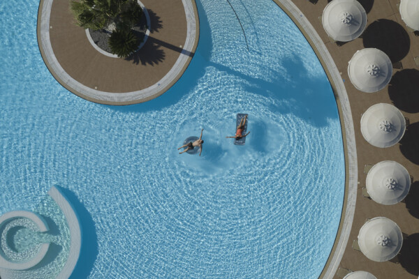 Aerial view of couple having fun floating on the swimming pool of Apollo Blue Hotel