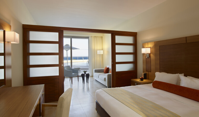 Interior view of a bedroom with sliding doors that separate the lounge area and terrace with private pool at Apollo Blue Hotel