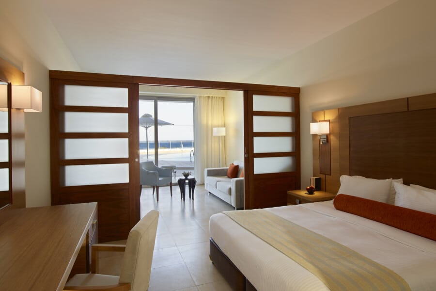 Interior view of a bedroom with sliding doors that separate the lounge area and terrace with private pool at Apollo Blue Hotel